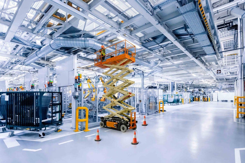Modern industrial warehouse with a scissor lift and various equipment.
